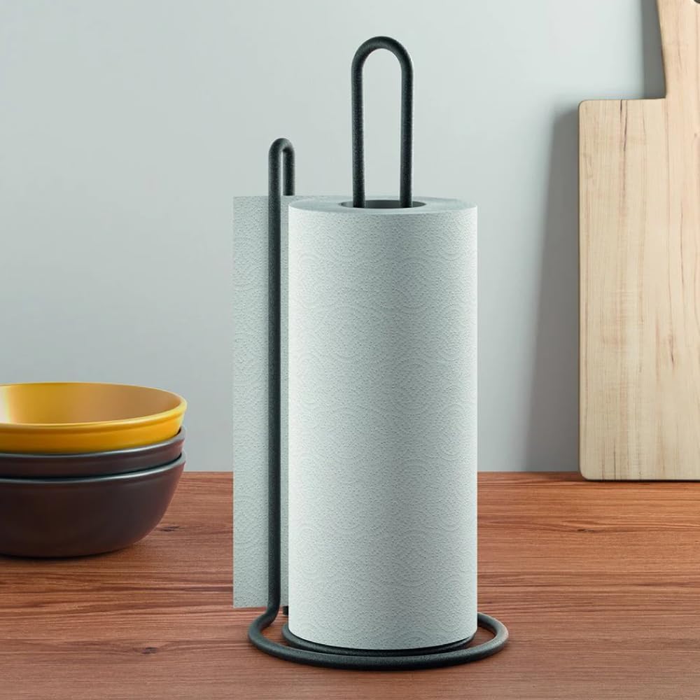 Paper towel holder placed on a kitchen counter beside bowls and cutting board.